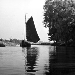 Torfschiff auf dem Hinter Tief, 1932 (Foto: Dietrich Janßen) Schwarz-weiß Fotografie eines Torfschiffes auf dem Wasser. Am rechten Ufer stehen große Bäume